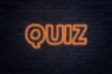Word QUIZ made of neon letters on black brick background