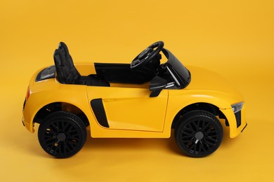 Child's electric toy car on yellow background