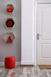 Photo of Shelves with different accessories on grey wall in hallway. Interior design