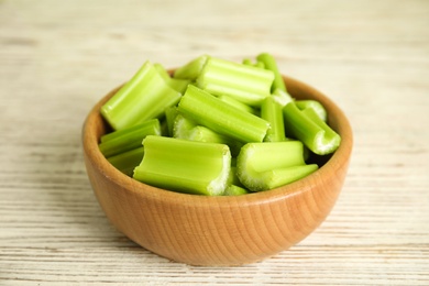 Photo of Cut celery in bowl on white wooden table