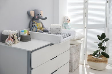 Chest of drawers with changing pad and tray in nursery. Baby room interior design