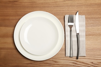 Empty dishware and cutlery on wooden background, top view. Table setting