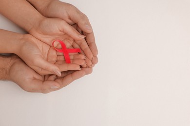 Couple holding pink ribbon on white background, top view with space for text. Breast cancer awareness