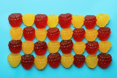 Delicious gummy raspberry candies on light blue background, flat lay