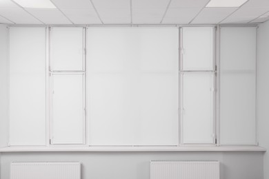 Windows covered with white roller blinds indoors