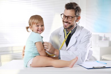 Pediatrician examining baby with stethoscope in clinic