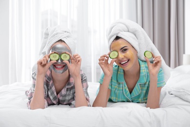 Young friends with facial masks having fun in bedroom at pamper party
