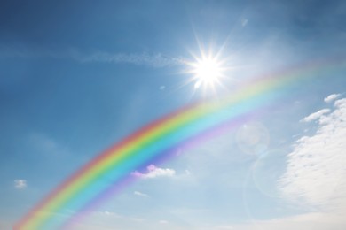 Beautiful rainbow in blue sky with white clouds on sunny day