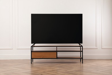 Photo of Modern TV on cabinet near white wall indoors. Interior design