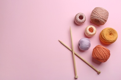 Photo of Clews of threads and knitting needles on color background, flat lay. Sewing stuff