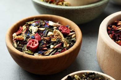 Bowls with different herbal teas on grey table