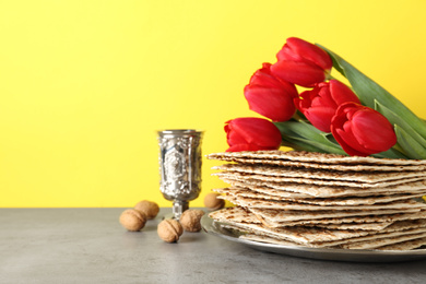 Passover matzos, goblet, walnuts and tulips on grey table, space for text. Pesach celebration