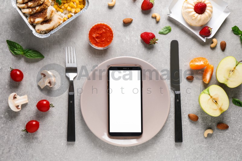Flat lay composition with Smartphone and products on grey table, mockup for design. Healthy food delivery