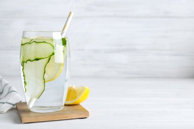 Refreshing water with cucumber, lemon and mint on white table, space for text