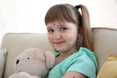 Little girl with chickenpox sitting on sofa at home