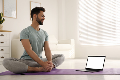 Man practicing yoga while watching online class at home during coronavirus pandemic. Social distancing
