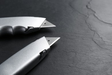 Two utility knives on black table. Space for text