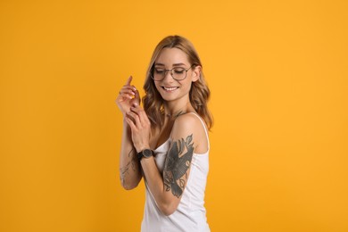 Beautiful woman with tattoos on body against yellow background