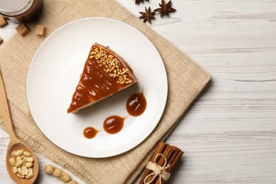 Photo of Tasty cheesecake with caramel and nuts served on white wooden table, flat lay. Space for text