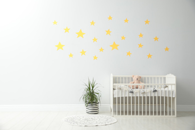 Minimalist room interior with baby crib and decor elements. Space for text