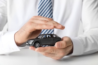 Male insurance agent holding toy car, closeup
