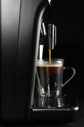 Making coffee with modern espresso machine on grey table against black background