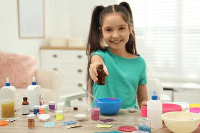 Cute little girl making slime toy at table indoors