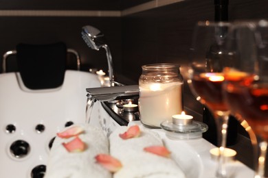 Candles and towels on tub in bathroom, space for text. Romantic atmosphere