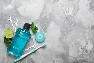 Flat lay composition with mouthwash and other oral hygiene products on grey marble background. Space for text
