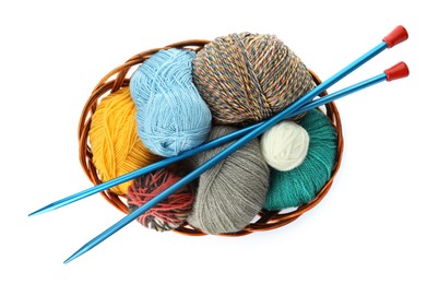 Photo of Different balls of woolen knitting yarns and needles in wicker basket on white background, top view