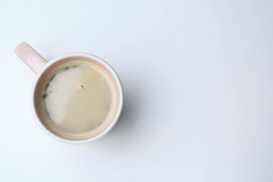 Mug of freshly brewed hot coffee on white background, top view. Space for text