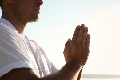 Man meditating against blue sky, closeup. Nature healing power