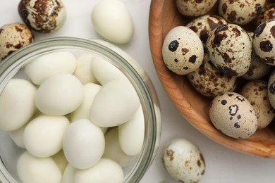 Photo of Unpeeled and peeled boiled quail eggs on white table, flat lay
