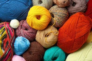 Different balls of woolen knitting yarns as background, top view