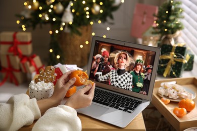 Photo of MYKOLAIV, UKRAINE - DECEMBER 25, 2020: Woman with tangerine watching The Witches  movie on laptop at home, closeup. Cozy winter holidays atmosphere
