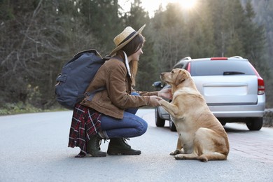 Photo of Happy woman and adorable dog on road. Traveling with pet