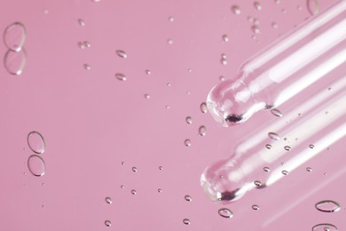 Photo of Pipette near serum drops on beautiful mirror, closeup with space for text. Toned in pink