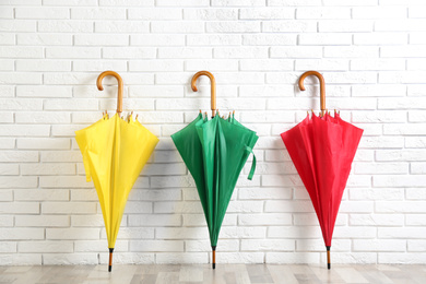Beautiful colorful umbrellas near white brick wall