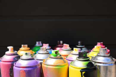 Used cans of spray paint on dark background, space for text. Graffiti supplies