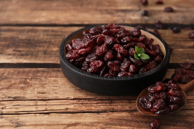 Photo of Tasty dried cranberries and leaves on wooden table