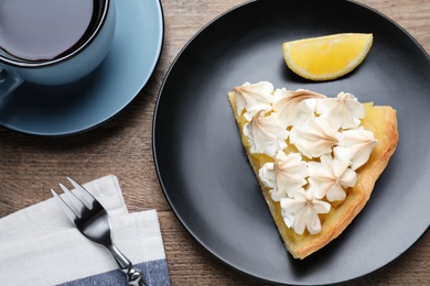 Piece of delicious lemon meringue pie served on wooden table, flat lay