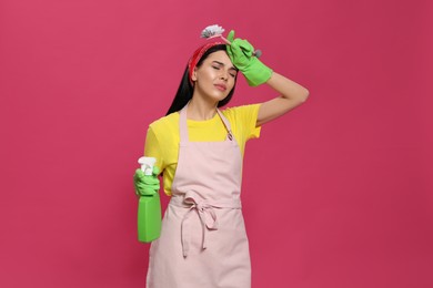 Young housewife with detergent and brush on pink background