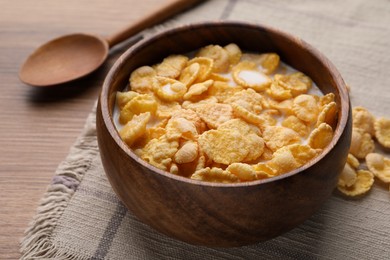 Tasty cornflakes with milk in bowl served on wooden table, closeup