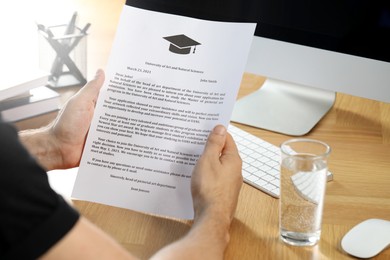Student with acceptance letter from university at wooden table indoors, closeup