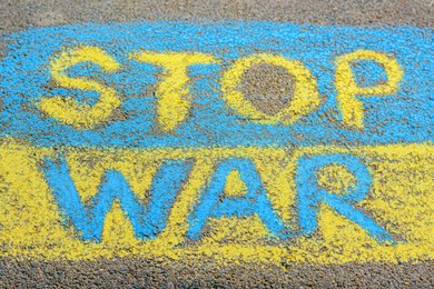 Ukrainian flag with words Stop War drawn with colorful chalks on asphalt outdoors, closeup