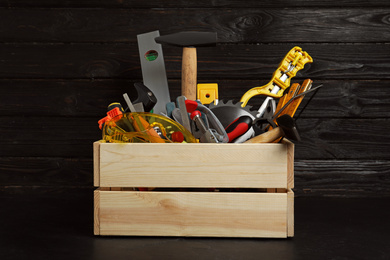Wooden crate with different carpenter's tools on black table