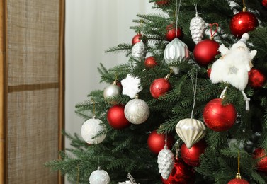 Christmas tree decorated with beautiful baubles indoors
