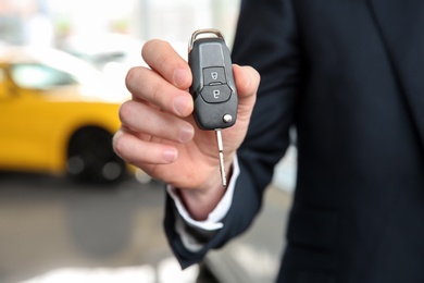 Businessman with key in dealership. Buying new car