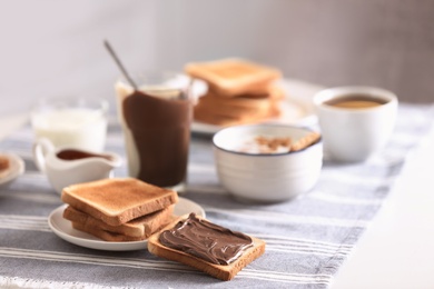 Delicious breakfast with toasts and chocolate paste on table