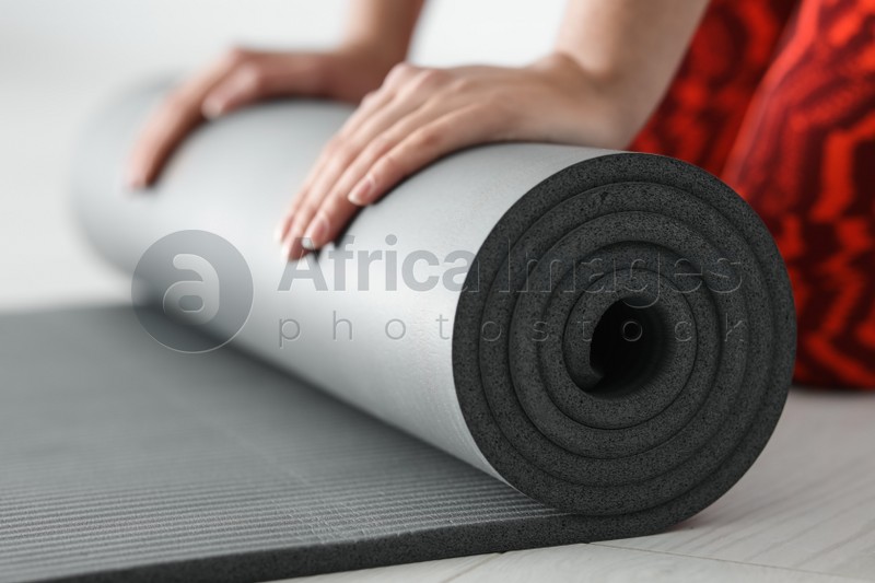 Young woman rolling yoga mat, closeup of hands